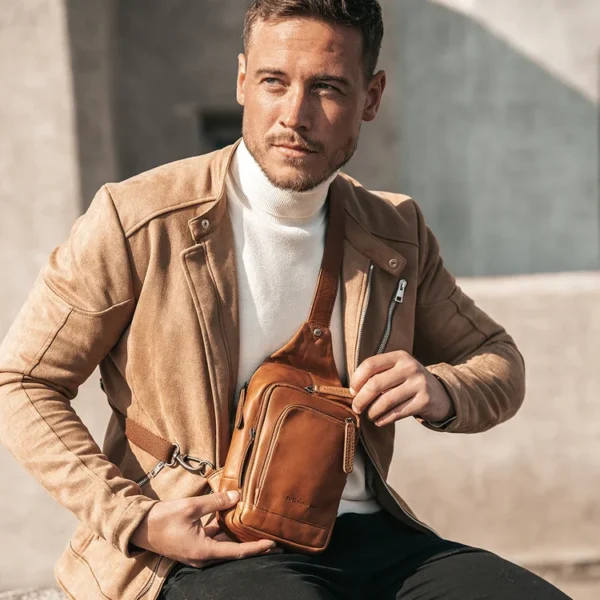 The Chesterfield RIGA Þessi crossbody taska úr leðri og er fullkominn ferðafélagi í borgarferð, hátíð eða útileguna! Alltar nauðsynjar þínar innan seilingar og á öruggan stað. Þú getur notað crossbody töskuna á mismunandi vegu, annað hvort með töskuna að framan eða með töskuna á bakinu. Crossbody taskan er með rúmgott aðalhólf og alls fjóra vasa með rennilás. Axlabandið er stillanlegt og er með karabínu neðst. Ásamt extra breiðu axlarólinni veitir þetta auka þægindi og auðveldan burð.
